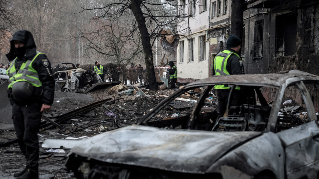 Police officers stand next to a destroyed car at the site of a damaged residential building following a missile strike in Kyiv (Kiev), Ukraine, 13 December 2023